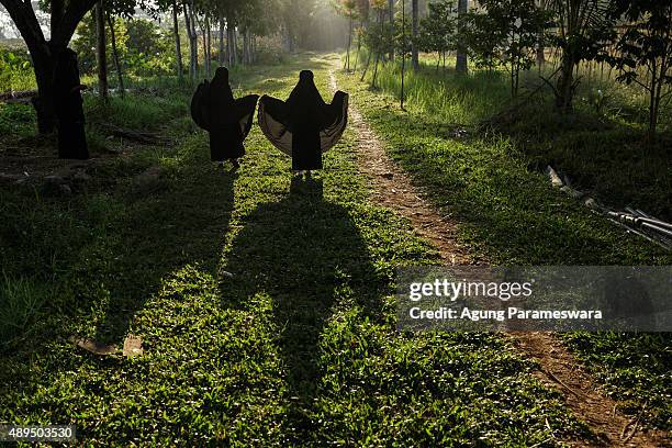 Two girl from the Islamic commune An-Nadzir walk to attend Eid Al Adha mass prayer at Mawang Lake, Gowa Regency on September 22, 2015 in Makassar,...