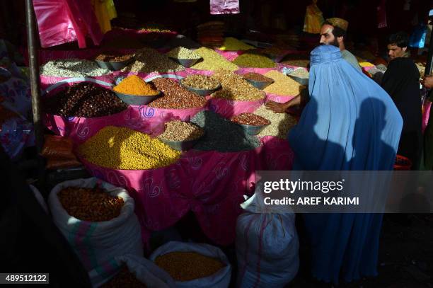 In this photograph taken on September 21, 2015 an burqa-clad Afghan woman buys dry fruits ahead of the sacrificial Eid al-Adha festival in Herat...