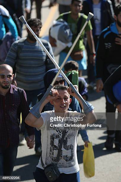 Migrant celebrates with his crutches as he and hundreds of migrants who arrived by train at Hegyeshalom on the Hungarian and Austrian border walk the...