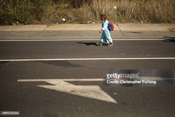 Young girl straggles behind as hundreds of migrants who arrived by train at Hegyeshalom on the Hungarian and Austrian border walk the four kilometres...