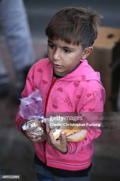 Young boy carries an armful of food given out by the Hungrian Red Cross as hundreds of migrants who arrived by train at Hegyeshalom on the Hungarian...
