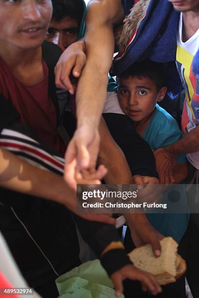 Migrants clamour for bread given out by the Hungrian Red Cross, as hundreds of migrants who arrived by train at Hegyeshalom on the Hungarian and...