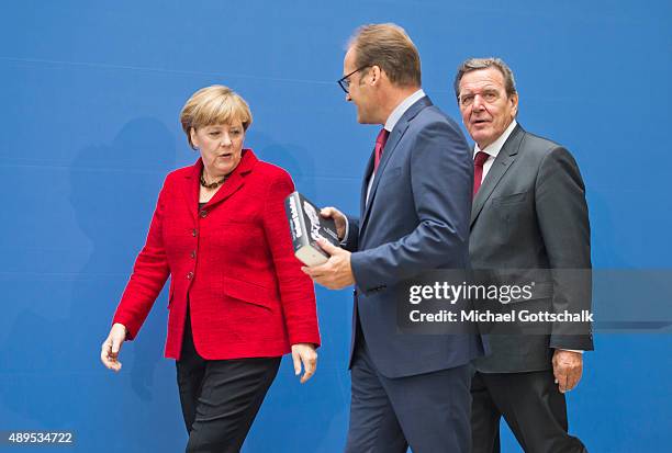 Former German Chancellor Gerhard Schroeder and German Chancellor Angela Merkel attends the presenation of 'Die Biographie' of 'The Biography' by...