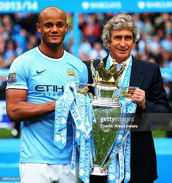 Vincent Kompany of Manchester City poses with manager Manuel Pellegrini and the Barclays Premier League trophy after the Barclays Premier League...