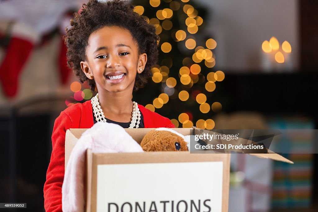 African American child holding box of toy donations at Christmastime