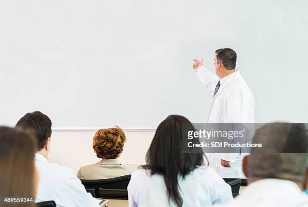 mature doctor giving lecture during healthcare conference or lecture - lecturer whiteboard stock pictures, royalty-free photos & images