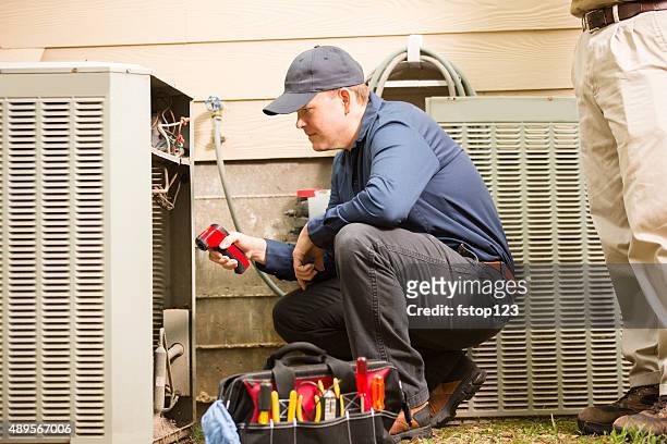 air conditioner repairmen work on home unit. blue collar workers. - hvac bildbanksfoton och bilder