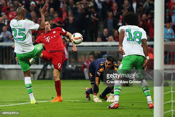 Robert Lewandowski of Muenchen scores his team's third goal against Naldo, Dante and goalkeeper Diego Benaglio of Wolfsburg during the Bundesliga...