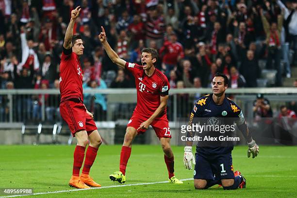 Robert Lewandowski of Muenchen celebrates his team's first goal with team mate Thomas Mueller as goalkeeper Diego Benaglio of Wolfsburg reacts during...