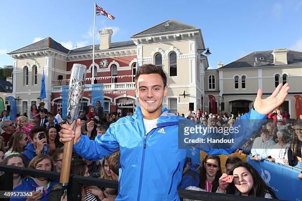 In this handout image provided by Glasgow 2014 Ltd, British diver Tom Daley carries the Commonwealth Games Baton with as it arrives into St Aubins...