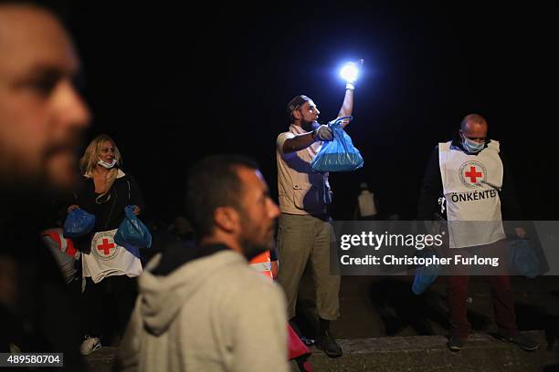 Migrants who arrived on the third train today, at Hegyeshalom on the Hungarian and Austrian border, are given food by volunteers as they walk the...