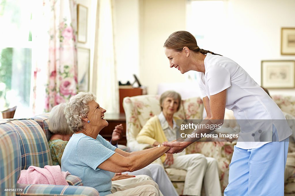 Happy caretaker assisting senior woman