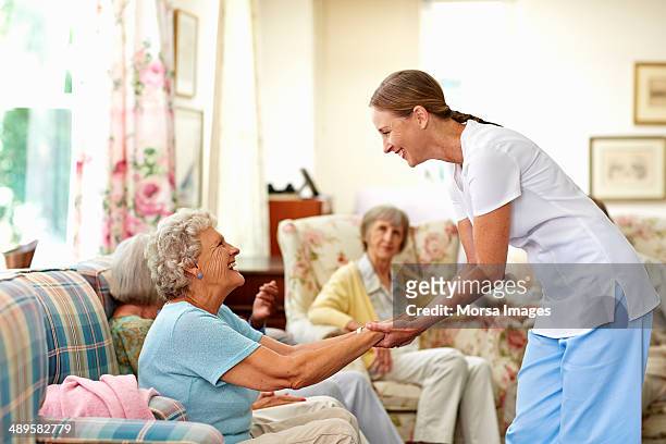 happy caretaker assisting senior woman - three people on couch stock pictures, royalty-free photos & images