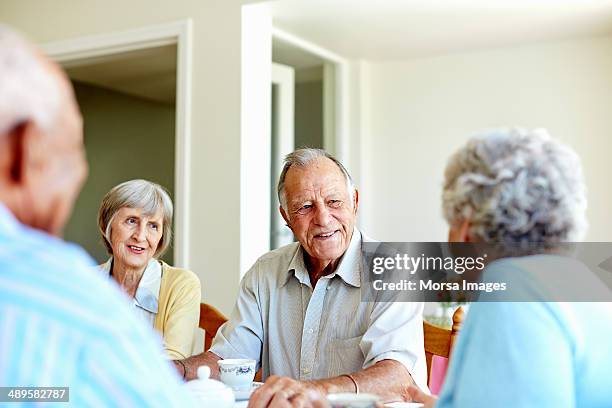 seniors spending leisure time in nursing home - senior social gathering stock pictures, royalty-free photos & images