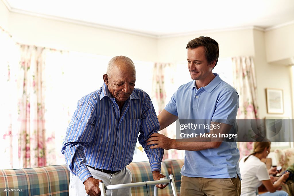 Caretaker assisting senior man with walker