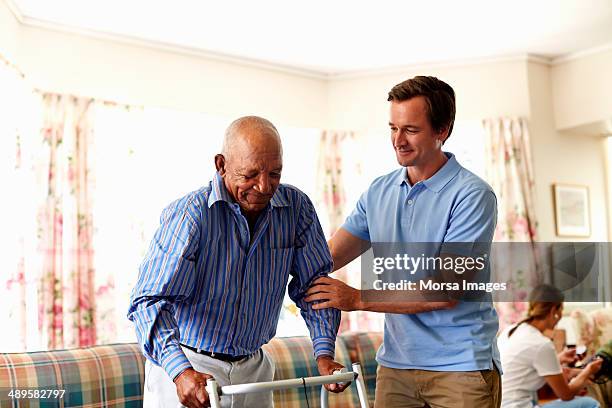 caretaker assisting senior man with walker - gåstol bildbanksfoton och bilder