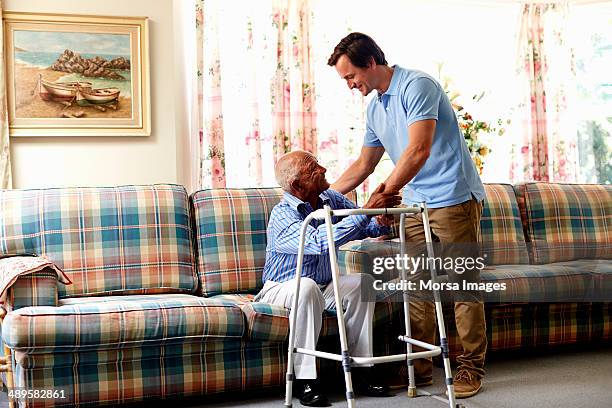 caretaker helping senior man with walker - hauswart stock-fotos und bilder