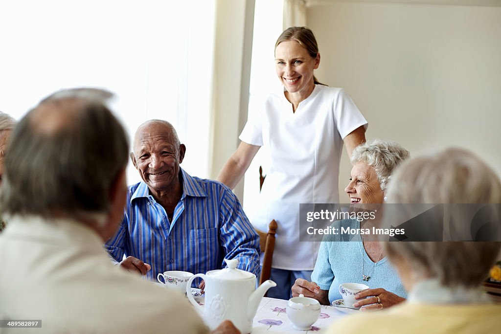 Caretaker with senior people enjoying coffee break