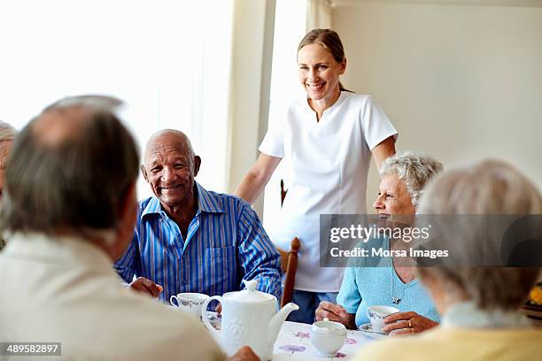 caretaker with senior people enjoying coffee break - rentnersiedlung stock-fotos und bilder