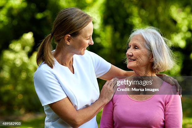 caretaker consoling senior woman in park - janitor stock pictures, royalty-free photos & images