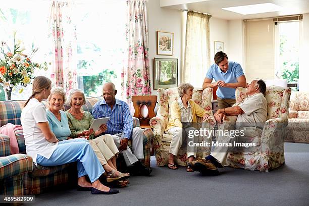 caretaker with retired people in nursing home - retirement village stock pictures, royalty-free photos & images