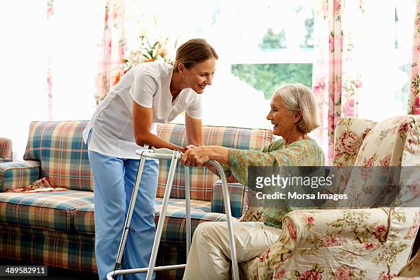 caretaker assisting senior woman with walker - bidello foto e immagini stock