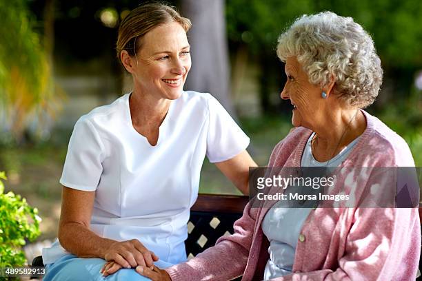 happy caretaker and senior woman in park - bidello foto e immagini stock