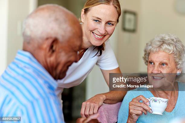 caretaker with senior people in nursing home - bidello foto e immagini stock