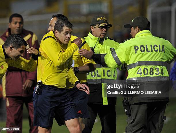 Argentine referee German Delfino leaves the field escorted by police at the end of the 2015 Sudamericana Cup football match between Colombia's...