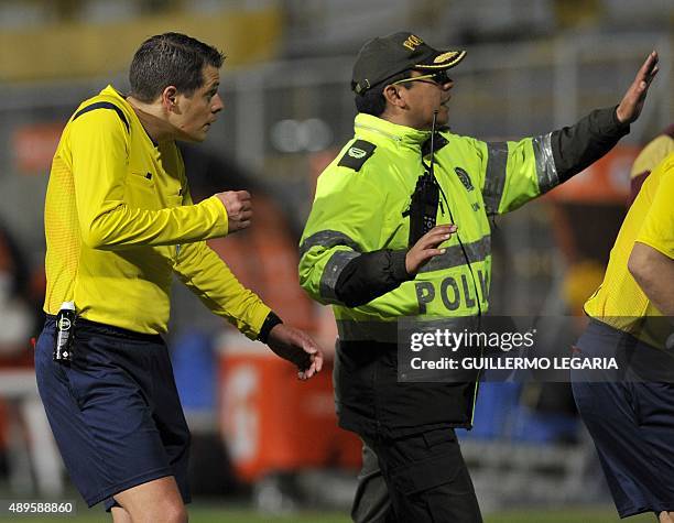 Argentine referee German Delfino leaves the field escorted by police at the end of the 2015 Sudamericana Cup football match between Colombia's...