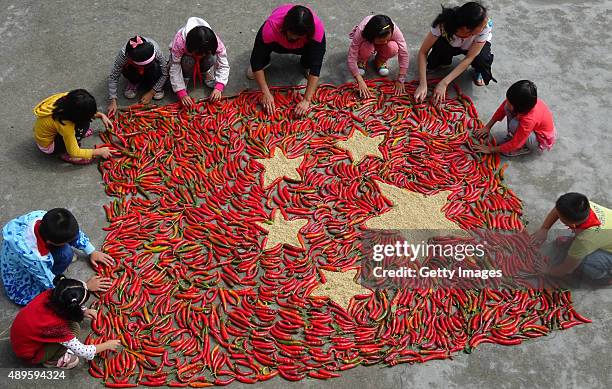 Villager Xie Qiaoying and another villager and students make a five-star red flag with red chillies at Beiji Village of Zixing City on September 22,...