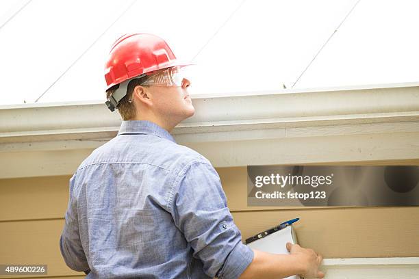 inspector or blue collar worker examines building roof.  outdoors. - quality control stock pictures, royalty-free photos & images