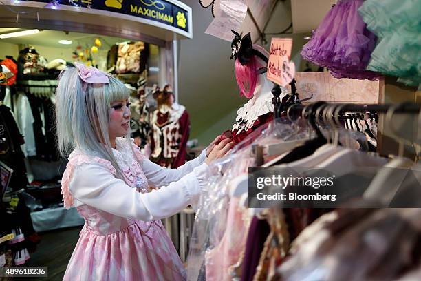 An employee arranges clothes on a mannequin at a clothing store on Takeshita Street in the Harajuku area of Tokyo, Japan, on Tuesday, Sept. 22, 2015....