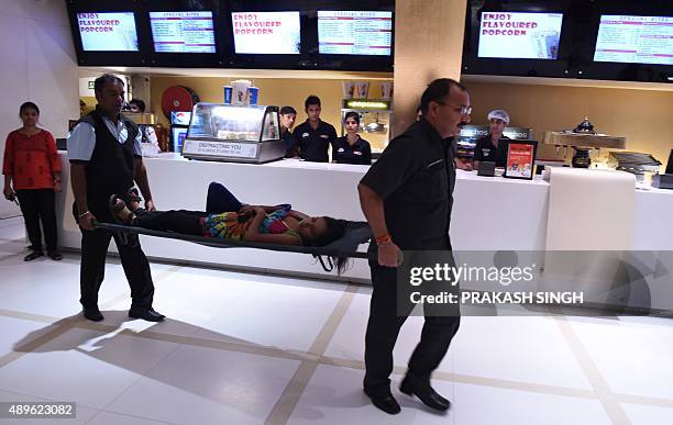 An Indian woman posing as a casualty is carried on a stretcher during a mock terror drill at a cinema hall in New Delhi on September 23, 2015.The...