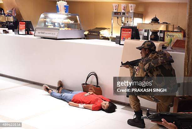 An Indian Delhi police SWAT commando is seen near a woman posing as a casualty during a mock terror drill at a cinema hall in New Delhi on September...