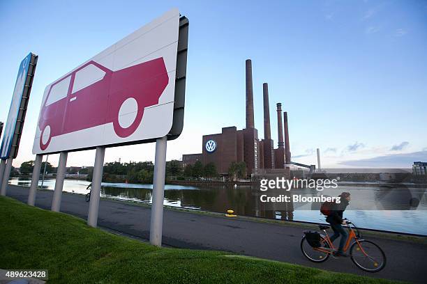 Cyclist passes along a tow path on the Aller river near the VW power plant, center, at the Volkswagen AG headquarters in Wolfsburg, Germany, on...