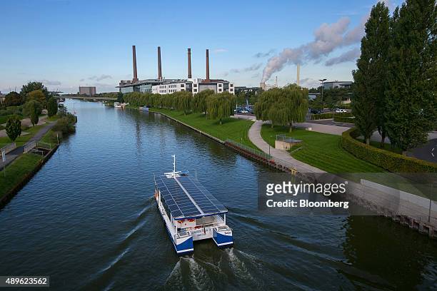 Solar panels sit on the roof of a sightseeing barge as the Volkswagen AG headquarters stands beyond on the bank of the Aller river in Wolfsburg,...