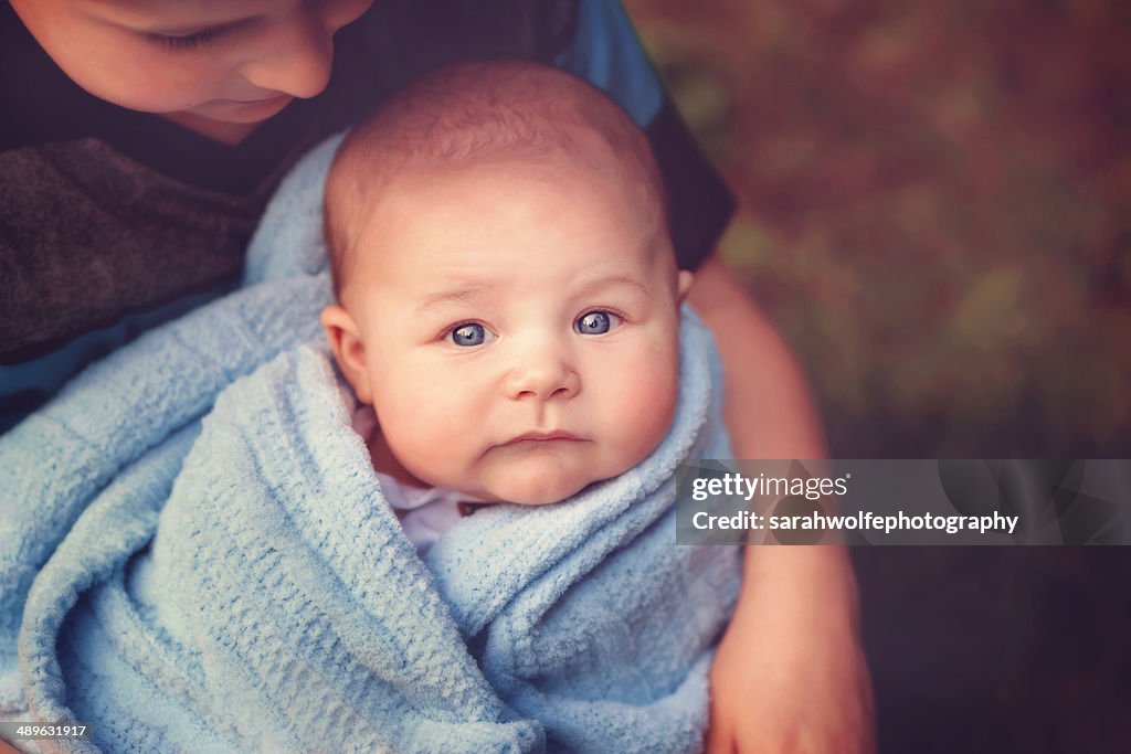 Child holding a baby in a blue blanket