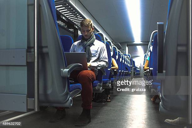 giovane bell'uomo lavorando sul portatile, mentre per il pendolarismo di lavoro - pendolare foto e immagini stock