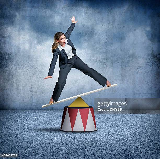 businesswoman balancing on a circus pedestal - balance stock pictures, royalty-free photos & images