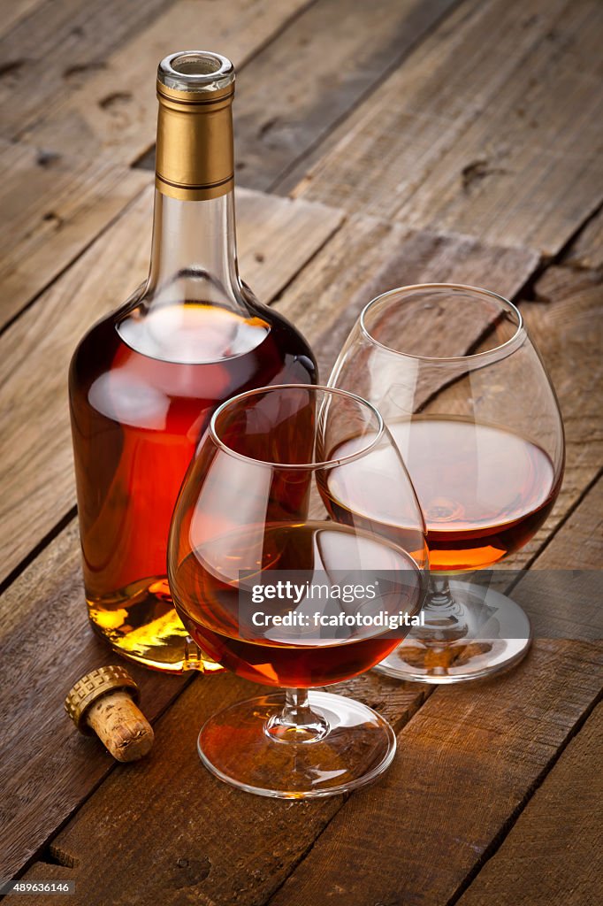 Cognac snifter with bottle on rustic wood table