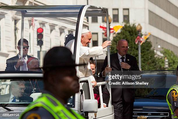 Pope Francis waves to the crowd as he rides in a popemobile along a parade route around the National Mall on September 23, 2015 in Washington, DC....