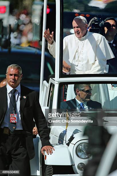Pope Francis waves to the crowd as he rides in a popemobile along a parade route around the National Mall on September 23, 2015 in Washington, DC....