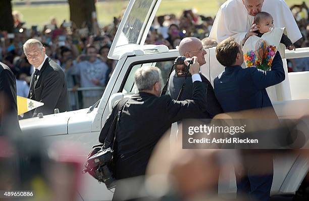 Pope Francis blesses a child handed to him during a parade on the streets around the Ellipse, south of the White House, September 23, 2015 in...