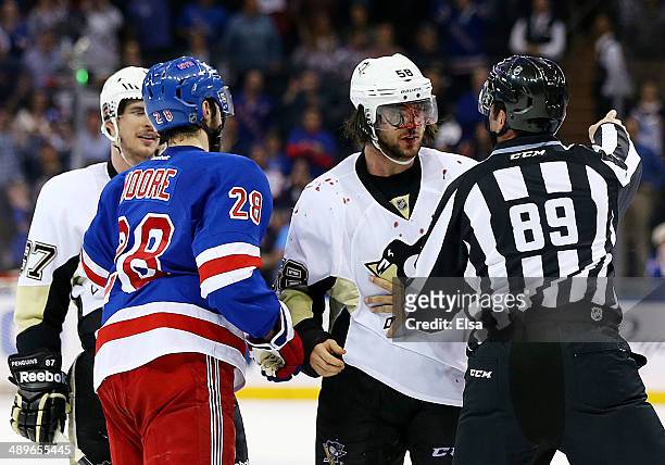 Linesman Steve Miller separates Kris Letang of the Pittsburgh Penguins and Dominic Moore of the New York Rangers after a fight at the end of their 3...