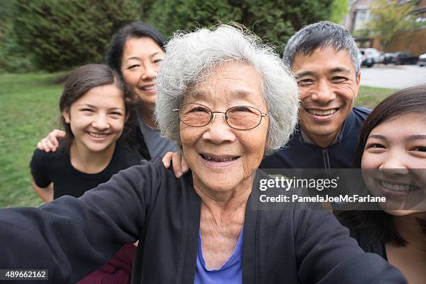 grandmother, children, grandchildren pose for selfie, care home in background - asian selfie stock pictures, royalty-free photos & images