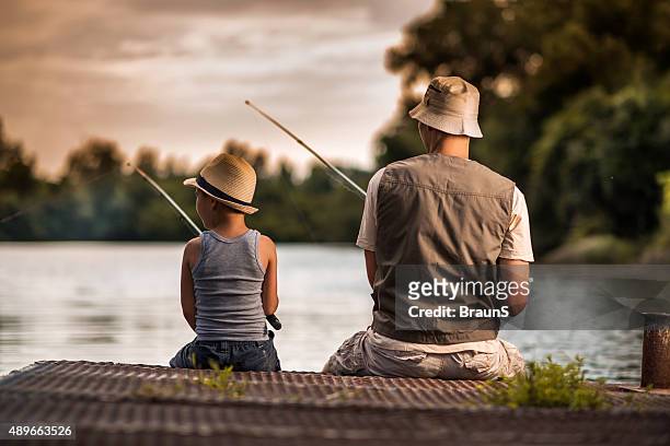 rear view of a father and son freshwater fishing. - freshwater fishing stock pictures, royalty-free photos & images