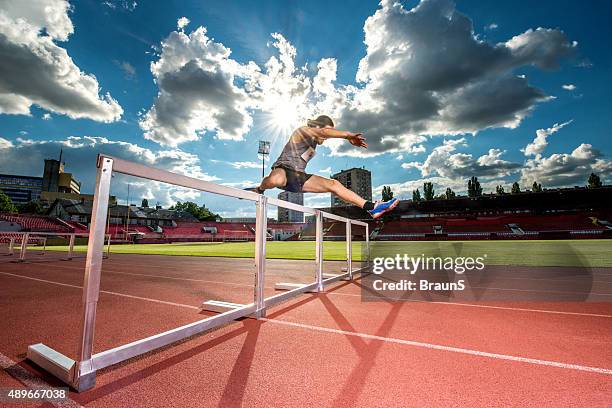 bestimmt sportler springen hindernisse auf ein rennen. - hurdles stock-fotos und bilder