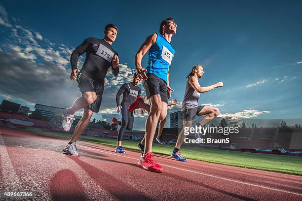 low angle view of sports team joggen auf eine stadion. - laufwettbewerb der männer stock-fotos und bilder