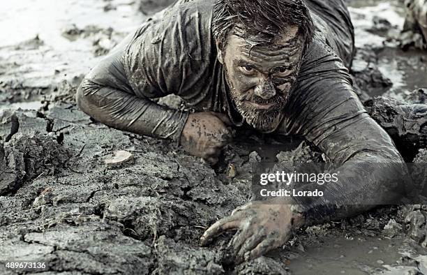 dark haired man crawling during a mud run - obstacle course stock pictures, royalty-free photos & images